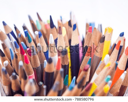 Detailed macro photograph view of the tops of a container of many sharpened colored art pencils from above.