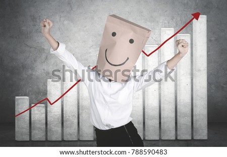 Unknown businesswoman with paper bag on her head while celebrating her success with growth finance graph background