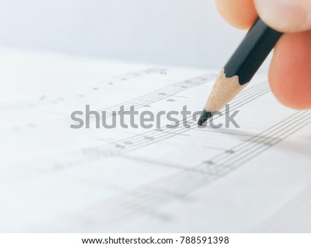 Pensil. Pensil in the hand. Pensil write Notes Of Melody. Composer Comes Down a Song and Records Musical Notes Of Melody On A Paper Leaf by Pensil. Royalty-Free Stock Photo #788591398