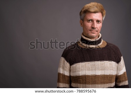 Studio shot of man with blond hair wearing turtleneck sweater against gray background