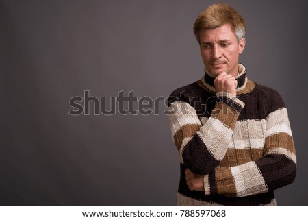 Studio shot of man with blond hair wearing turtleneck sweater against gray background