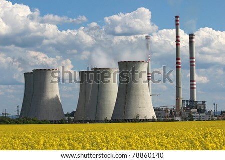 coolin tower and chimney of coal power plant over yellow field