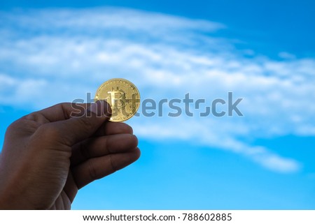 Bitcoin. Royalty high quality free stock image of bitcoin. Close focus of hand holding a bitcoin with copy space for text or advertising on blue sky background