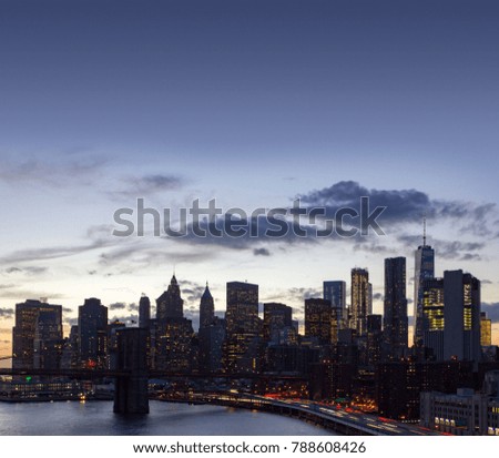 New York City skyline lights at dusk with the Brooklyn Bridge and Manhattan skyscrapers 