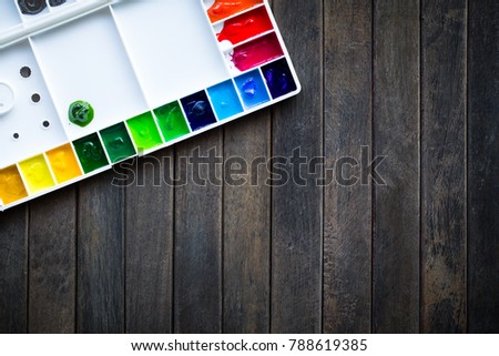 Top view of paintbrushes palette and watercolor paints with wooden table. picture for add text message.