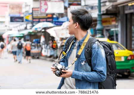 Asian male tourist photographer backpacking in Khao san road,  Bangkok, Thailand on holidays