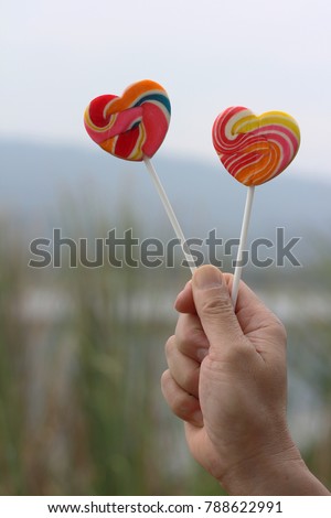heart lollipop in men hand and blurry background