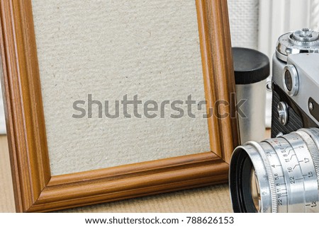 detailed view of empty wooden photo frame and old vintage camera 