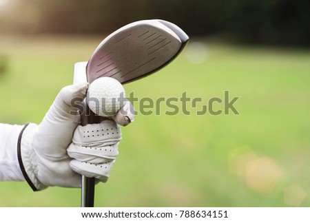 Golf background concept. Closeup golf ball and golf club on hand with glove with blurred green grass on background. Picture for add text message. Backdrop for design art work.