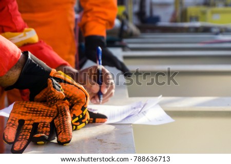 A foreman reviews and put a signature to a safety checklist prior to heavy lifting activity on a construction barge at oil field