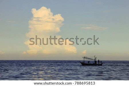 Beach landscape of Sanae beach with a boat and dramatic cloudy sky (Hua Hin, Thailand)