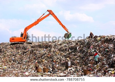 Backhoe working on garbage dump in landfill. People Working at Landfill site. Royalty-Free Stock Photo #788708755