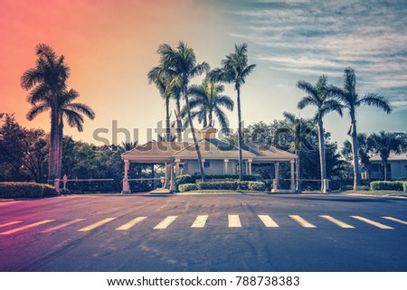 Guard entrance with asphalt road to gated community in South Florida. Light effect applied