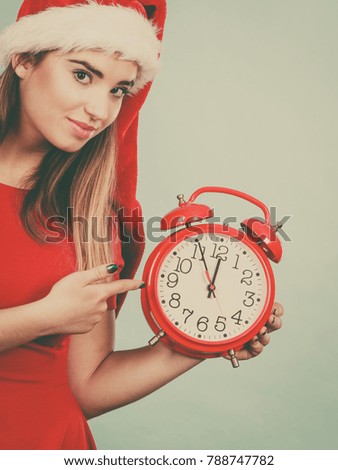Xmas, seasonal clothing, christmas time concept. Woman wearing Santa Claus helper costume holding big red clock, waiting for celebration