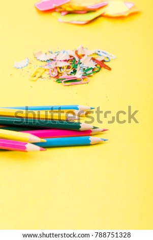Search idea concept. Colorful pencils, stickers, clips and on yellow background. Copy space. School supplies.