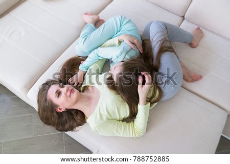 Mother and daughter lying on sofa and hugging