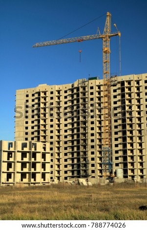 An image of a tower crane against the background of a house under construction.