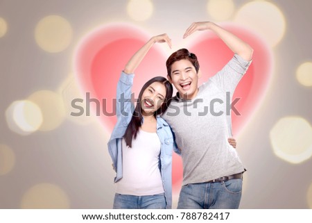 Romantic asian couple in love make heart with hand over blur light background