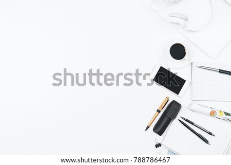Top view and close up of modern white office workplace with empty smartphone, supplies, headphones and other items. Leisure, hobby, break, work and occupation concept. Mock up