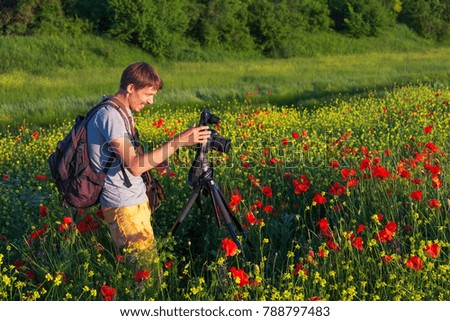 Photographer taking pictures of poppies in the field during sunset 