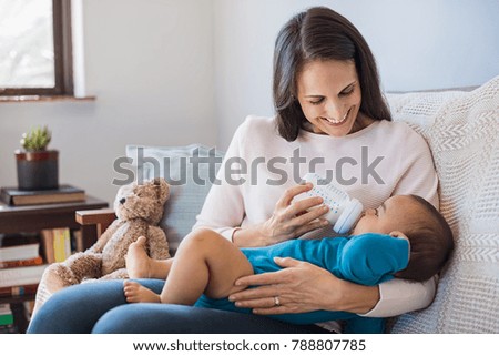 Mother holding and feeding baby from milk bottle. Portrait of cute newborn baby being fed by her mother using bottle. Loving woman giving to drink milk to her son. Royalty-Free Stock Photo #788807785
