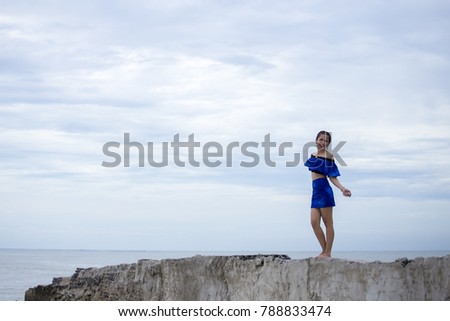 Cute Asian women wears fashion costume dress and takes pictures on the beach during travel around Thailand on summer season.