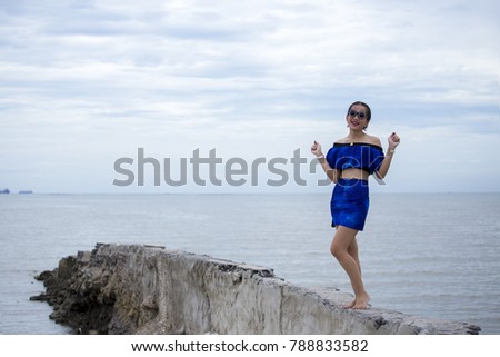 Cute Asian women wears fashion costume dress and takes pictures on the beach during travel around Thailand on summer season.