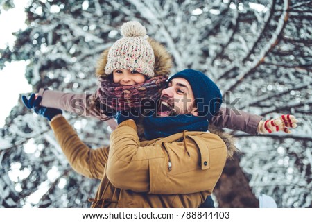 Handsome young dad and his little cute daughter are having fun outdoor in winter. Enjoying spending time together. Family concept.
