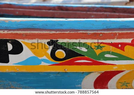 Details of colored wooden boats. Colorful planks of senegalese traditional boats. Patterns of bright colors used to paint the wood. Letters and lines and curves are painted for decoration.