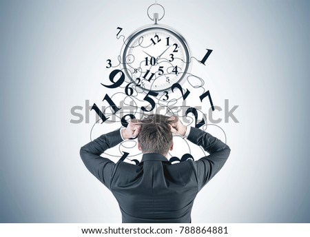 Portrait of a blond businessman wearing a suit and pulling out his hair in panic. A rear view. A gray wall with a broken stopwatch sketch