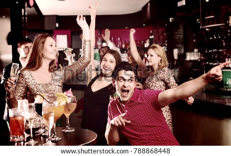 Portrait of  cheerful  smiling females and males having fun in the bar