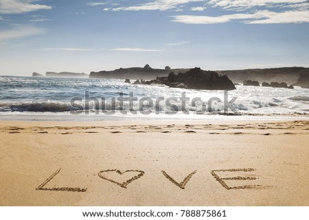 word love written on the seashore in the sand of a beautiful beach
