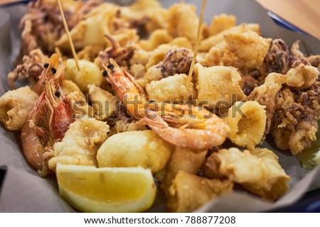 A typical Italian dish fried seafood: shrimp, squid, octopus and a slice of lemon. Italian fast food. Fish and chips Royalty-Free Stock Photo #788877208
