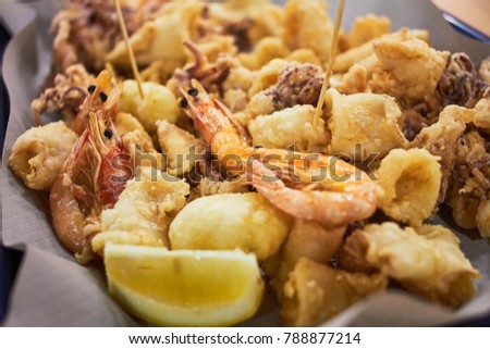 A typical Italian dish fried seafood: shrimp, squid, octopus and a slice of lemon. Italian fast food. Fish and chips Royalty-Free Stock Photo #788877214