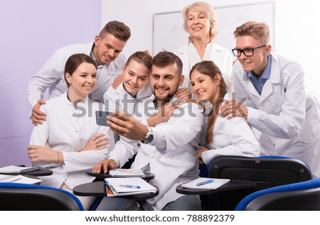 Ordinary students of medical faculty with female teacher making selfie indoors