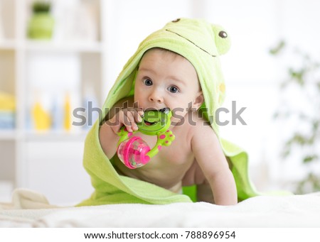 Baby boy with green towel after the bath biting toy. Royalty-Free Stock Photo #788896954