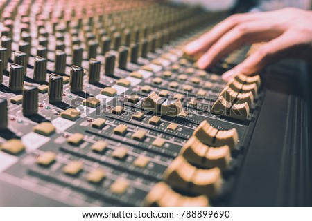 male sound engineer hands working on sound mixer, focus on fader. recording, broadcasting, music production background