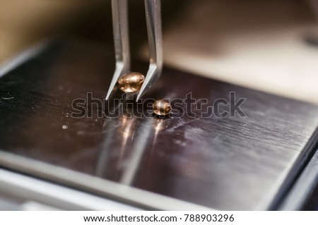 The work of jewelers. The jeweler weighs the copper granules on a digital scale. Selective focus. Macro photo.