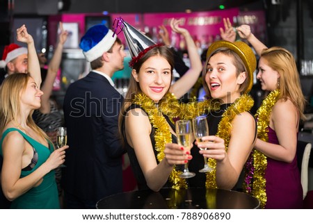 Portrait of females and males in caps and garlands in the night club