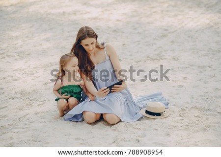 A beautiful young mother plays on the beach with her little daughter