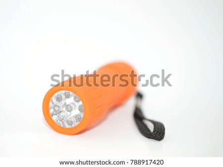 Small plastic orange flashlight with black holding string on the side