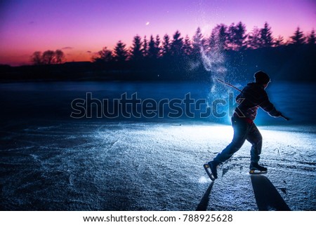Young hockey player on natural ice Sunset light in background. Silhouette sport hockey photo with edit space. Concept photo.