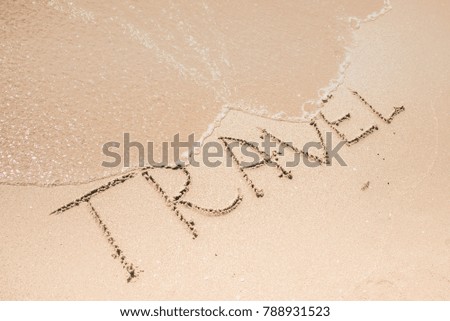 Travel word is written on the beach sand