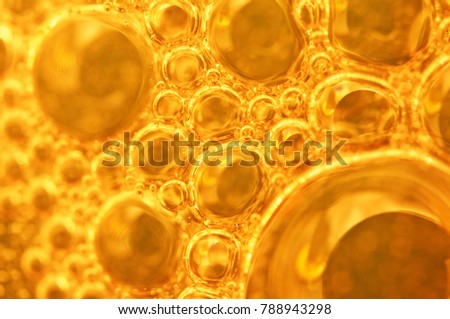 Golden background with big and small gold bubbles oil inside a gold liquid.