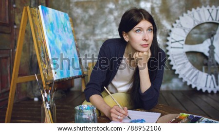 Young woman artist draw pictrure with watercolor paints and smile loking in window