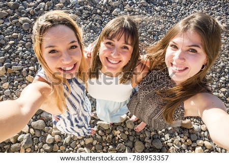 Aerial selfies for a group of three beautiful woman with a stone background. Happiness moment to catch some memories and post them on the social network