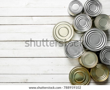 Tin cans with food. On white wooden table.