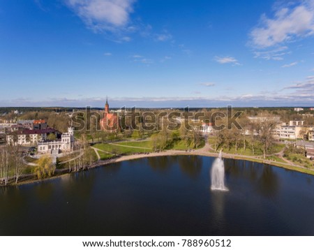 Aerial view over Druskininkai city lake fountain with city church and museum in the background, Lithuania. During spring time.