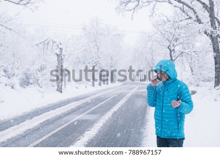 teenager with smartphone and blue jacket, snow day on the road