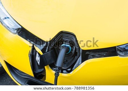 Yellow electric taxi charging in charging station.